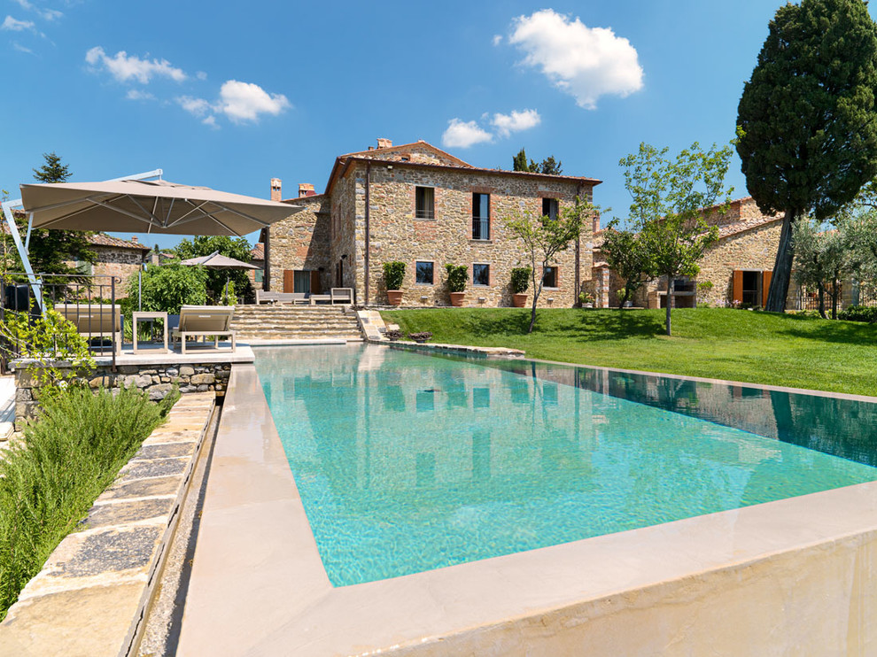 Diseño de piscina elevada de estilo de casa de campo grande rectangular en patio delantero con adoquines de hormigón
