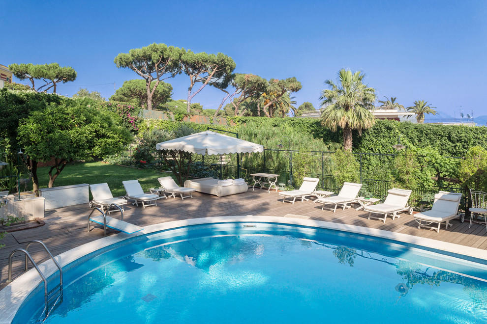 Imagen de piscina mediterránea grande con entablado