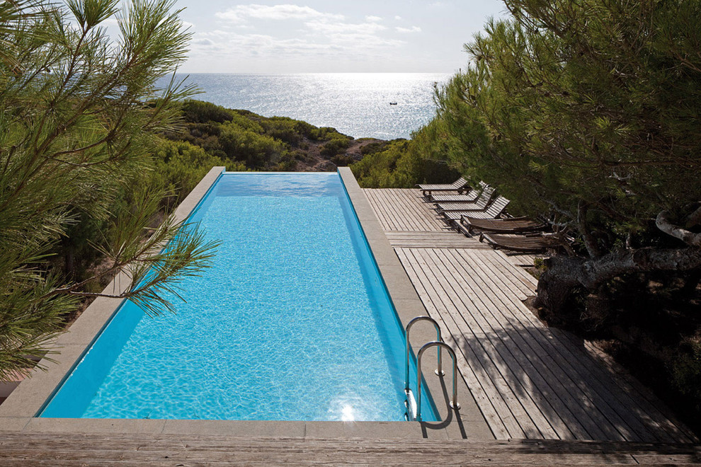На фото: прямоугольный бассейн-инфинити среднего размера на внутреннем дворе в средиземноморском стиле с домиком у бассейна и настилом