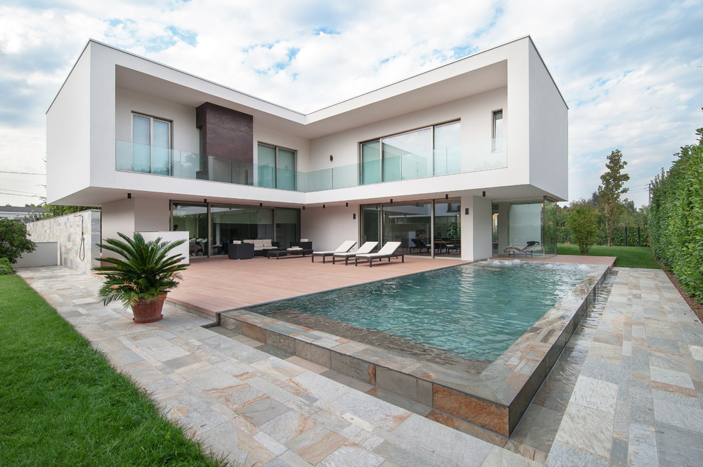 Diseño de piscina alargada actual extra grande rectangular en patio trasero con adoquines de piedra natural