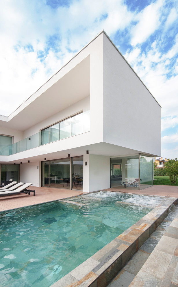 Esempio di un'ampia piscina monocorsia moderna rettangolare dietro casa con pavimentazioni in pietra naturale