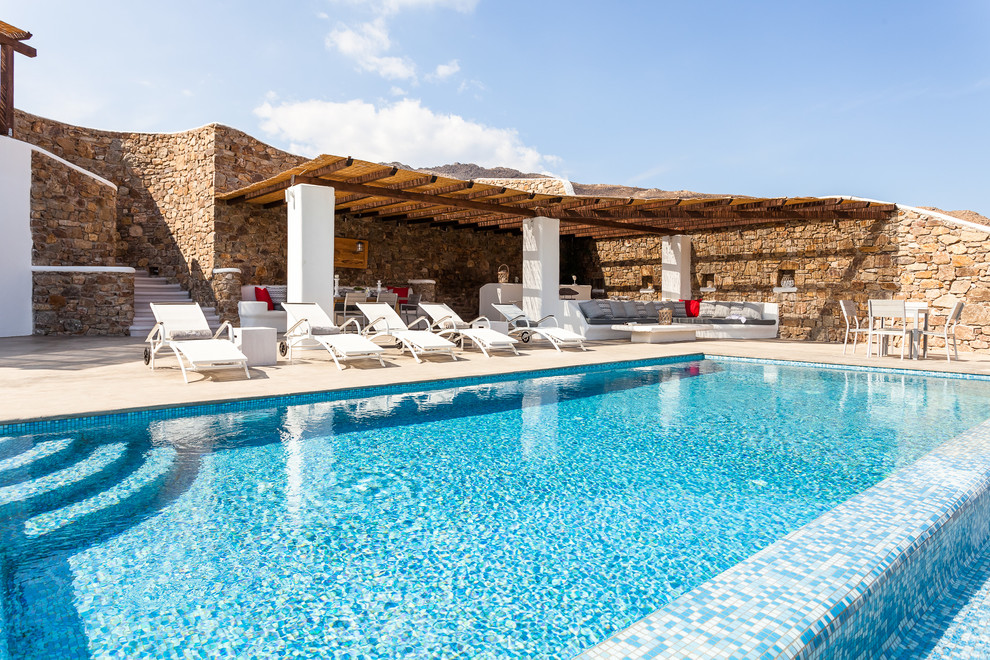 Ejemplo de piscina infinita mediterránea rectangular en patio trasero con suelo de baldosas