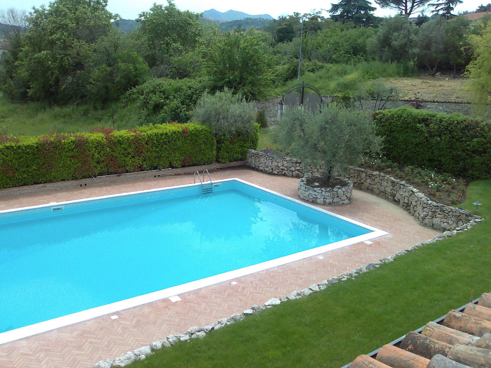 Imagen de piscina mediterránea grande rectangular con paisajismo de piscina y adoquines de ladrillo