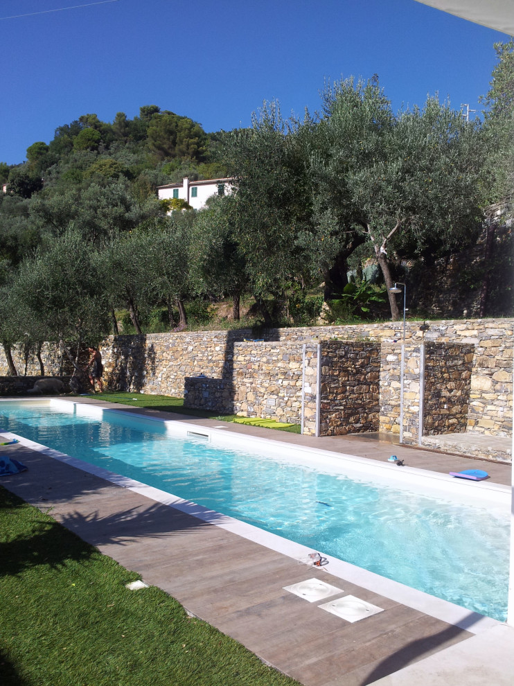 Immagine di una grande piscina a sfioro infinito mediterranea rettangolare davanti casa con una dépendance a bordo piscina e pavimentazioni in pietra naturale