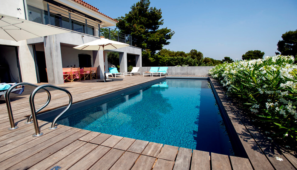 Стильный дизайн: прямоугольный бассейн в средиземноморском стиле с настилом - последний тренд