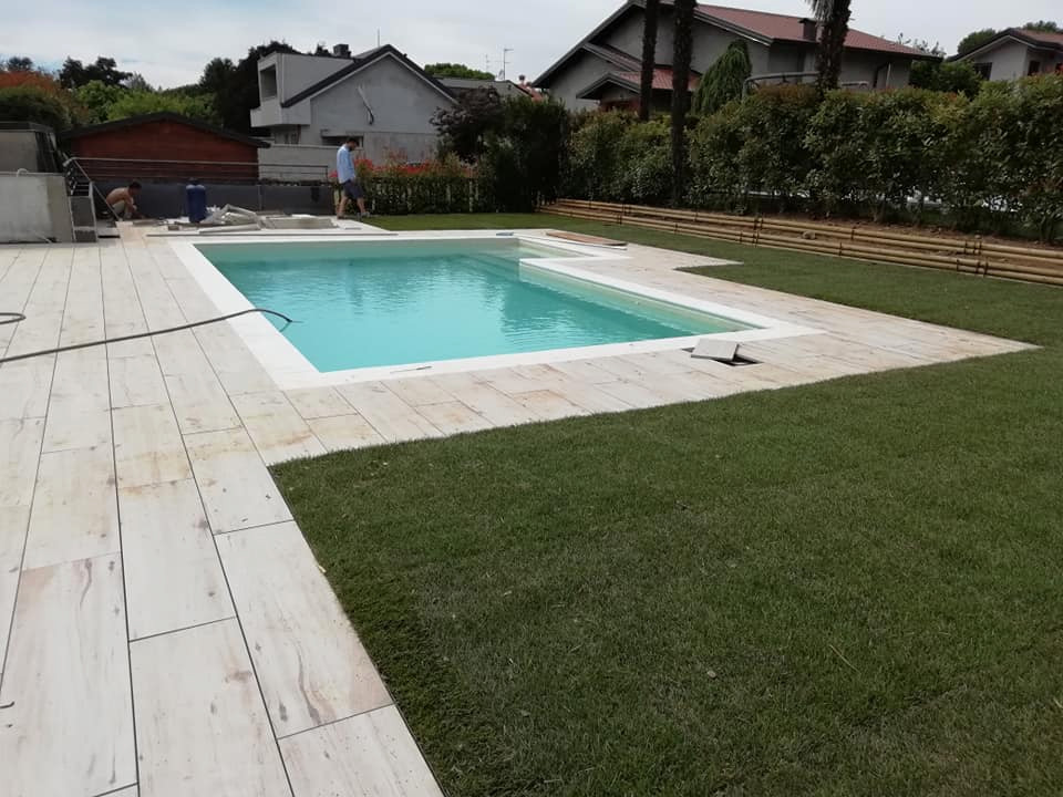 Imagen de piscina de tamaño medio en forma de L en patio trasero con privacidad y suelo de baldosas