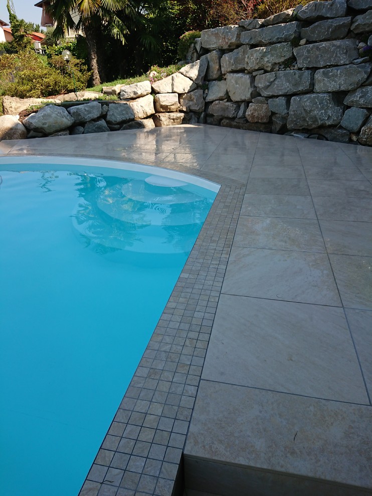 На фото: бассейн среднего размера, произвольной формы на боковом дворе в средиземноморском стиле с покрытием из плитки