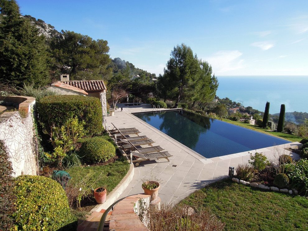 Modelo de casa de la piscina y piscina infinita mediterránea grande rectangular en patio trasero con suelo de baldosas