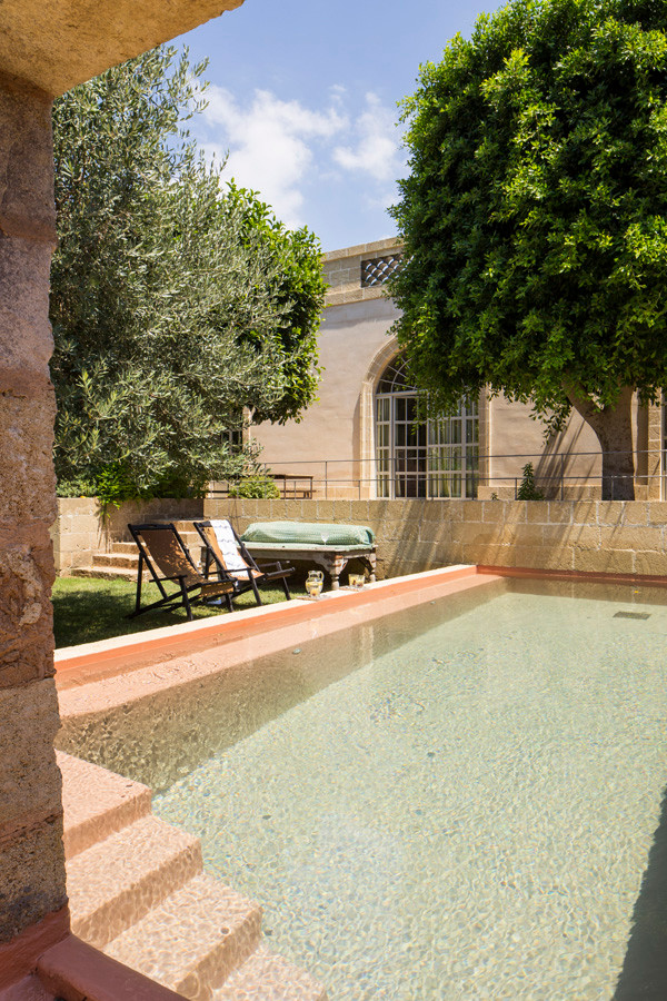Idée de décoration pour une grande piscine à débordement méditerranéenne rectangle avec une cour et des pavés en pierre naturelle.