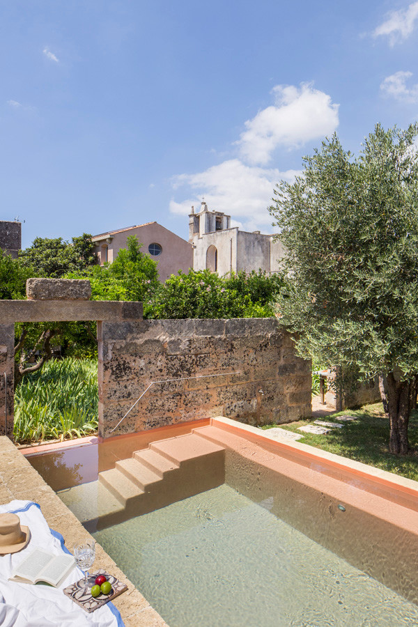 Esempio di una grande piscina a sfioro infinito mediterranea rettangolare in cortile con pavimentazioni in pietra naturale