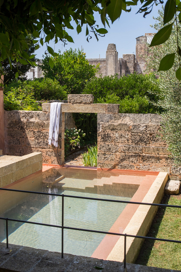 Ejemplo de piscina infinita mediterránea grande rectangular en patio con adoquines de piedra natural