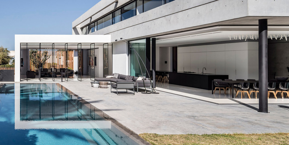Ejemplo de piscina infinita moderna extra grande en patio delantero con adoquines de piedra natural