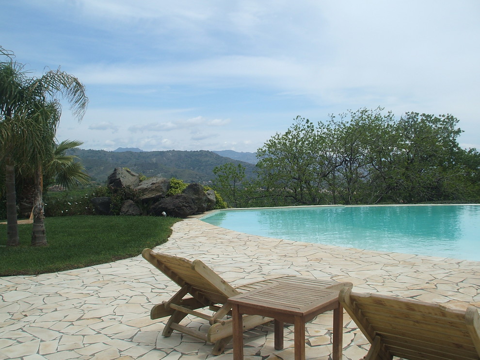 Modelo de piscina infinita mediterránea de tamaño medio a medida en patio lateral con paisajismo de piscina y adoquines de piedra natural