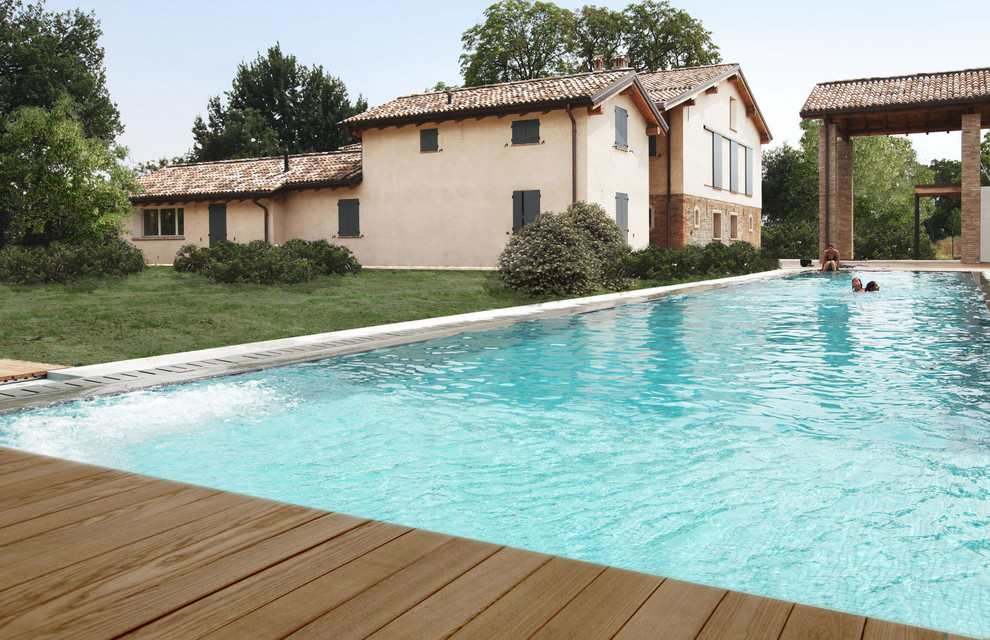 Foto di una grande piscina a sfioro infinito mediterranea rettangolare dietro casa con una dépendance a bordo piscina