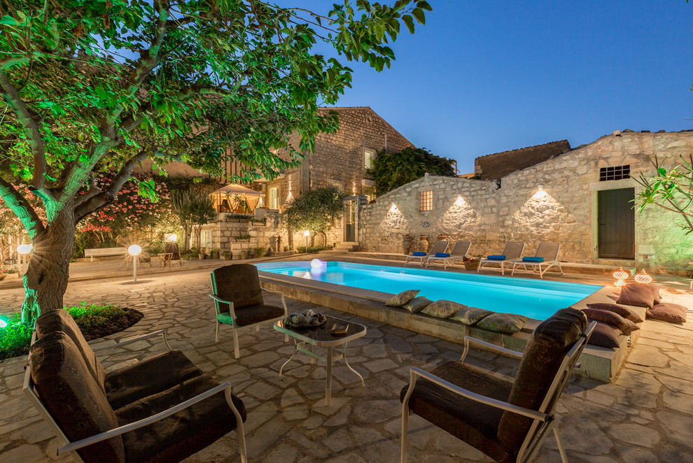 Mediterraner Pool hinter dem Haus in rechteckiger Form mit Natursteinplatten in Sonstige