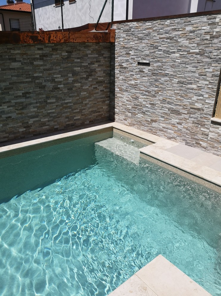Kleiner Moderner Pool hinter dem Haus in L-Form mit Wasserspiel und Natursteinplatten in Sonstige