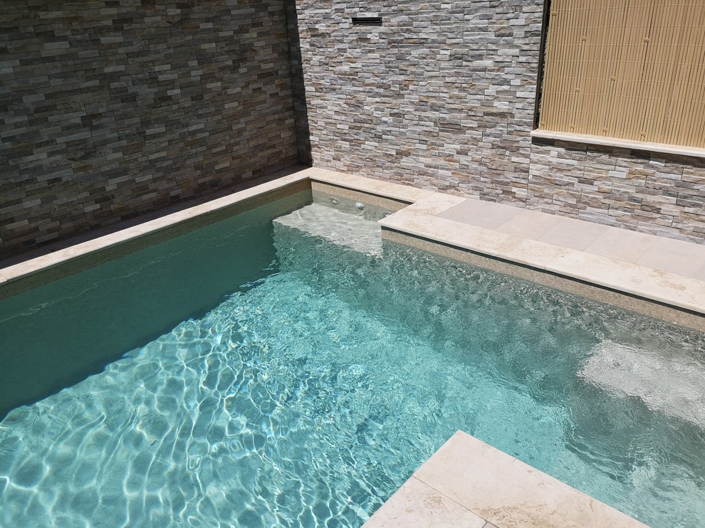 Small contemporary back l-shaped swimming pool in Other with a water feature and natural stone paving.