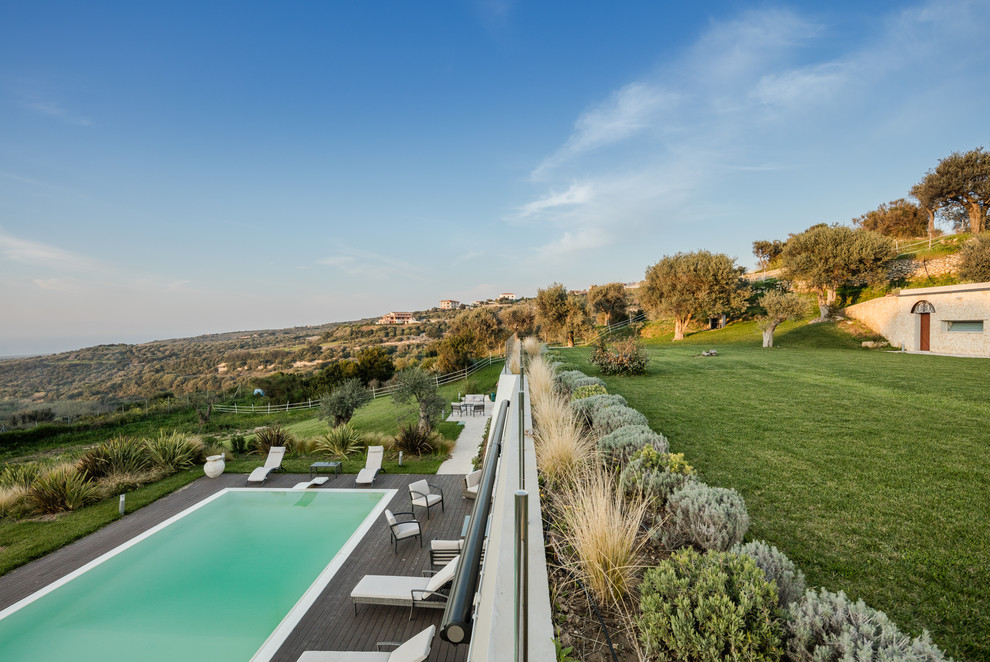 Immagine di una piscina a sfioro infinito moderna rettangolare di medie dimensioni e davanti casa con una dépendance a bordo piscina e pedane