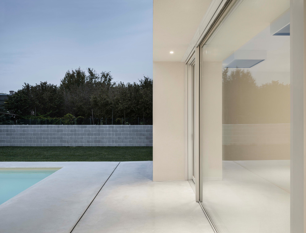 Réalisation d'une grande piscine design rectangle avec des solutions pour vis-à-vis, une cour et des pavés en béton.