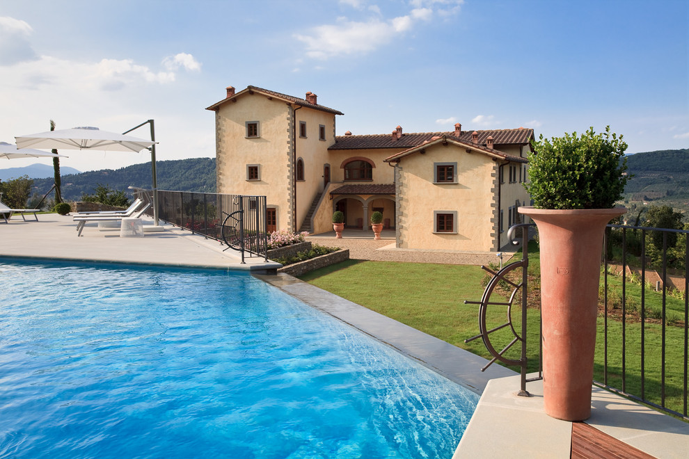 Pool - mediterranean backyard custom-shaped infinity pool idea in Florence with decking