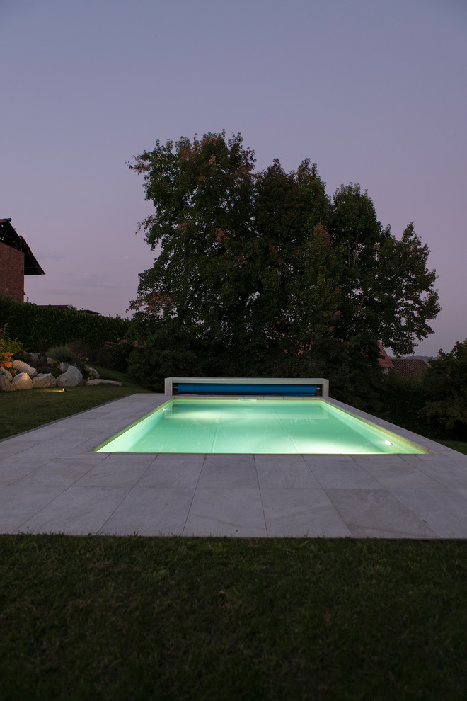 This is an example of a medium sized modern rectangular natural swimming pool in Milan with tiled flooring.