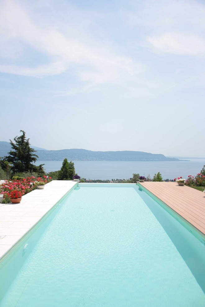 Esempio di una piscina a sfioro infinito minimal rettangolare di medie dimensioni e davanti casa con paesaggistica bordo piscina e pavimentazioni in pietra naturale