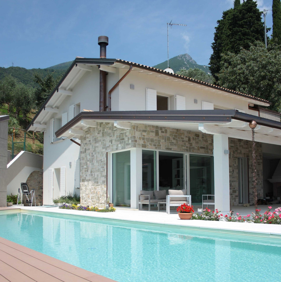 Ejemplo de casa de la piscina y piscina infinita minimalista rectangular en patio lateral con adoquines de piedra natural