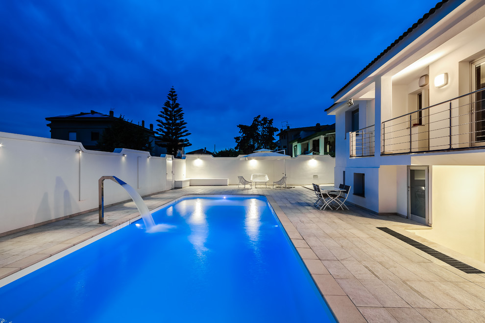 Idéer för en modern pool längs med huset, med en fontän och naturstensplattor