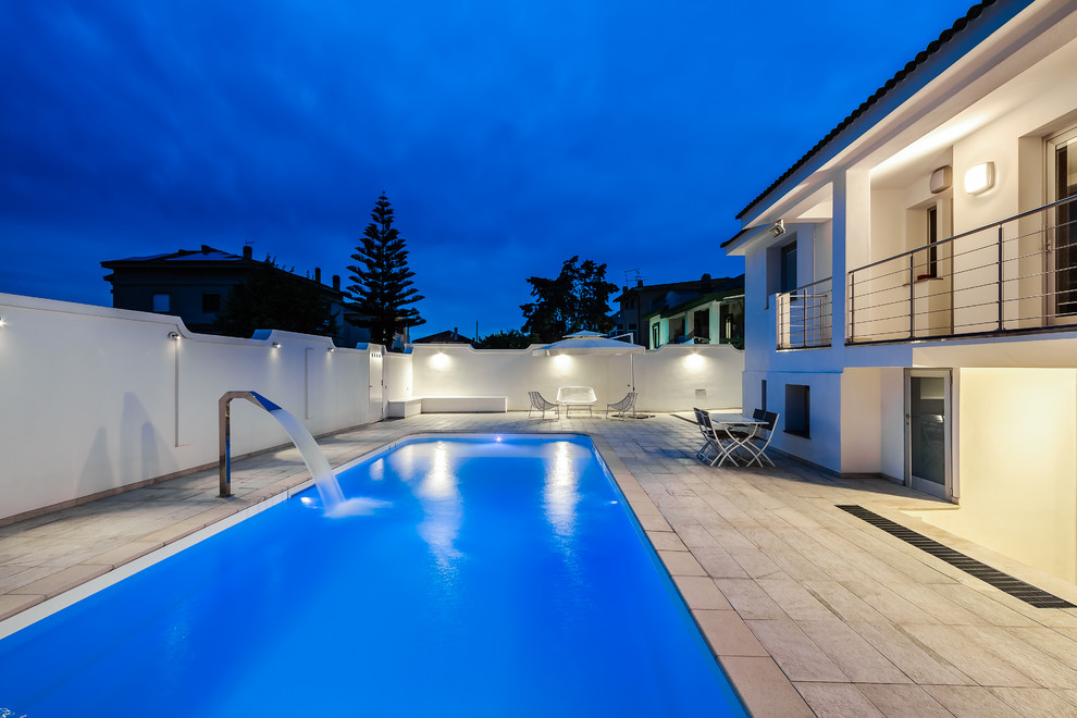 Aménagement d'une piscine latérale contemporaine avec un point d'eau et des pavés en pierre naturelle.