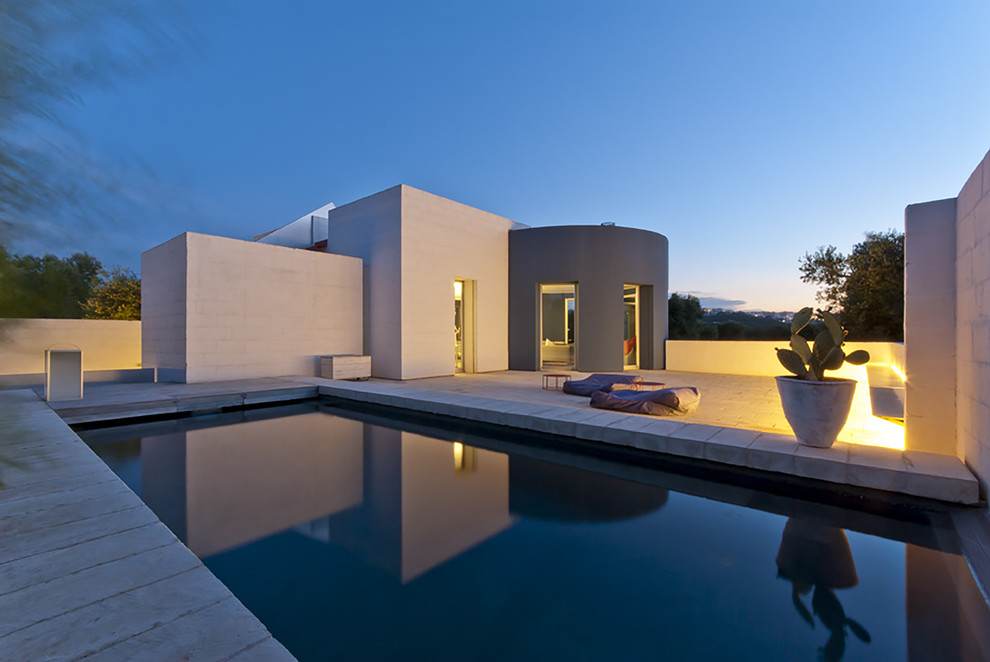 Immagine di una piscina design rettangolare di medie dimensioni e dietro casa con pavimentazioni in pietra naturale