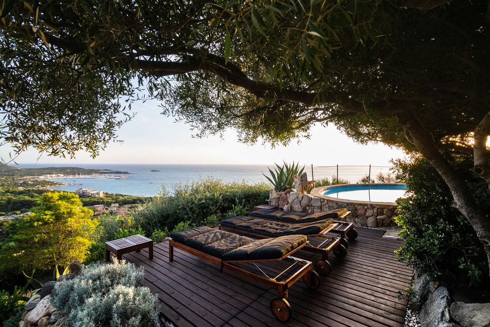 Cette image montre une piscine hors-sol et arrière méditerranéenne ronde avec une terrasse en bois.