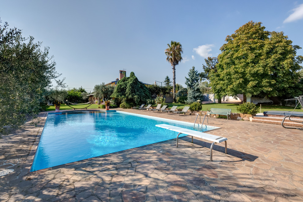 Exemple d'une grande piscine méditerranéenne rectangle avec des pavés en pierre naturelle.