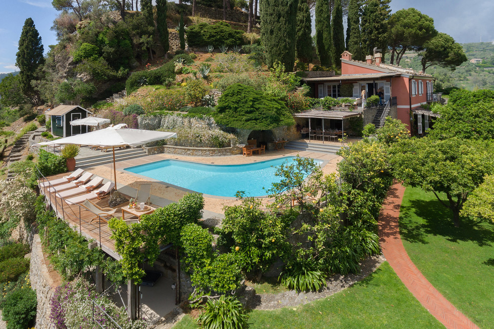 Imagen de piscina mediterránea en forma de L en patio trasero