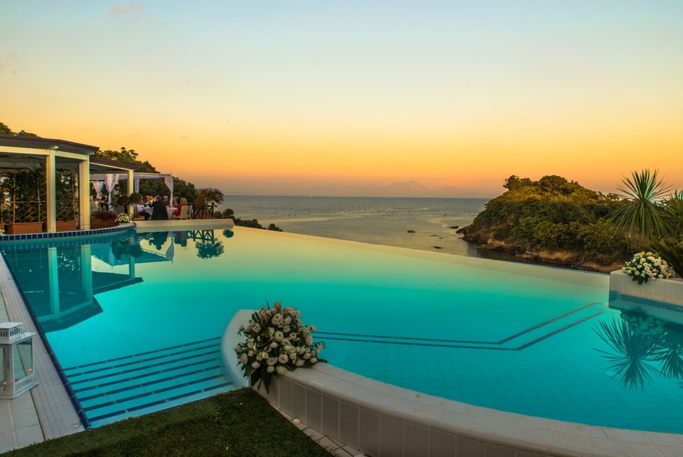 Foto di una piscina a sfioro infinito mediterranea personalizzata di medie dimensioni e in cortile con una dépendance a bordo piscina e piastrelle