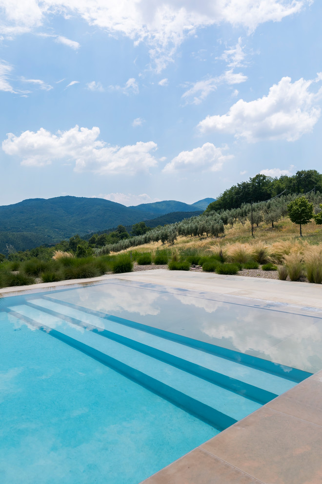 Ejemplo de piscina infinita rústica grande rectangular en patio trasero con adoquines de piedra natural