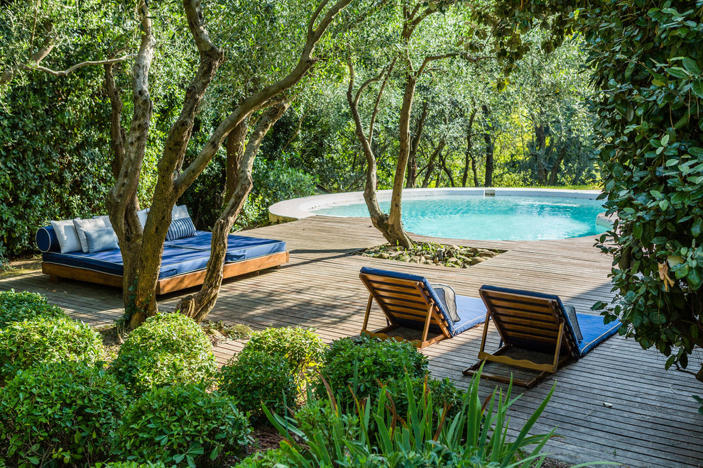 Modelo de piscina mediterránea redondeada en patio trasero con entablado