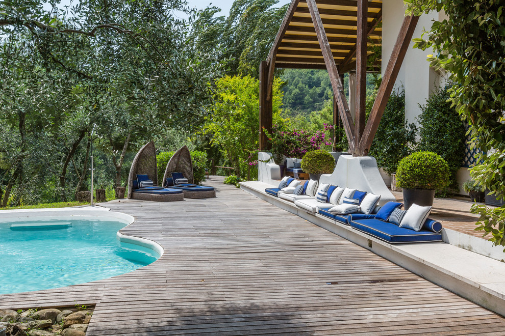 Diseño de piscina mediterránea redondeada en patio trasero con entablado