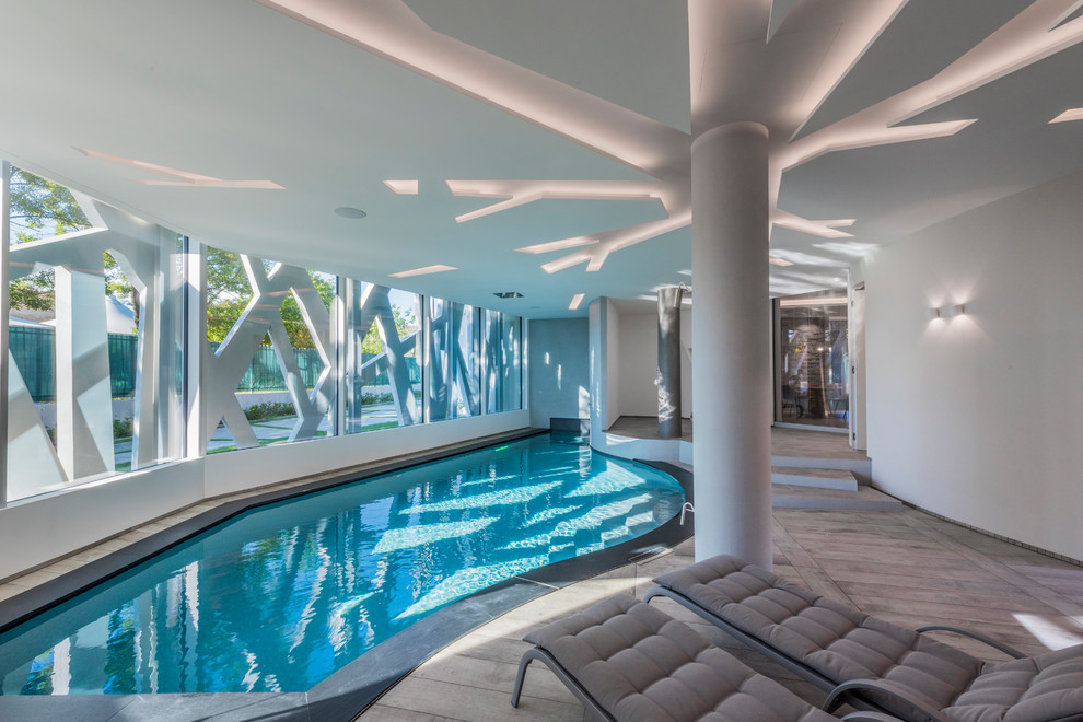 This is an example of a contemporary indoor custom shaped swimming pool in Other with decking.