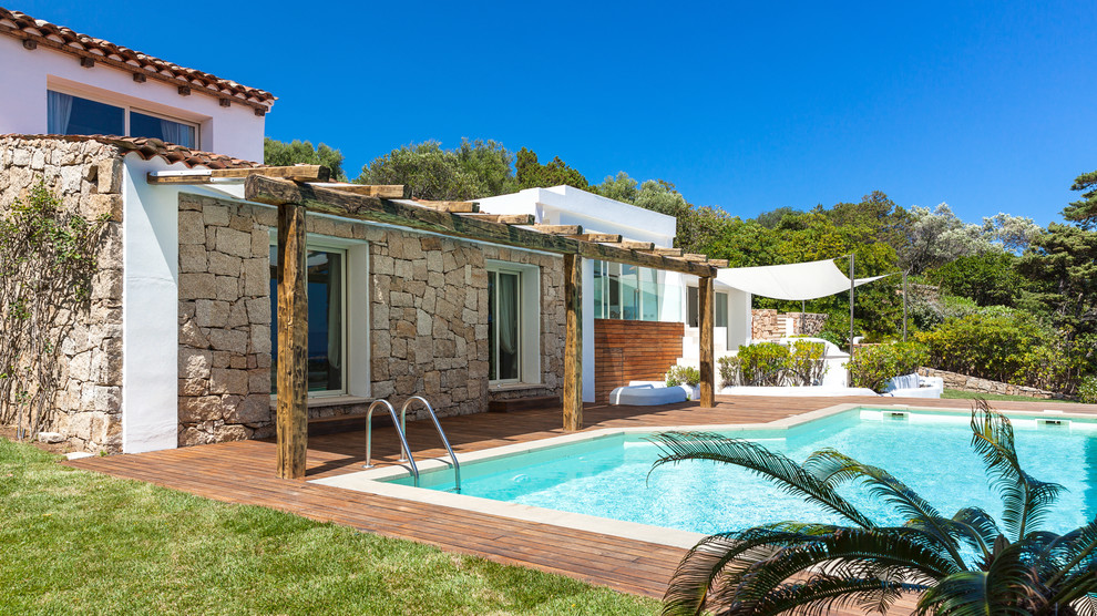 Immagine di una piscina mediterranea di medie dimensioni e dietro casa con pedane