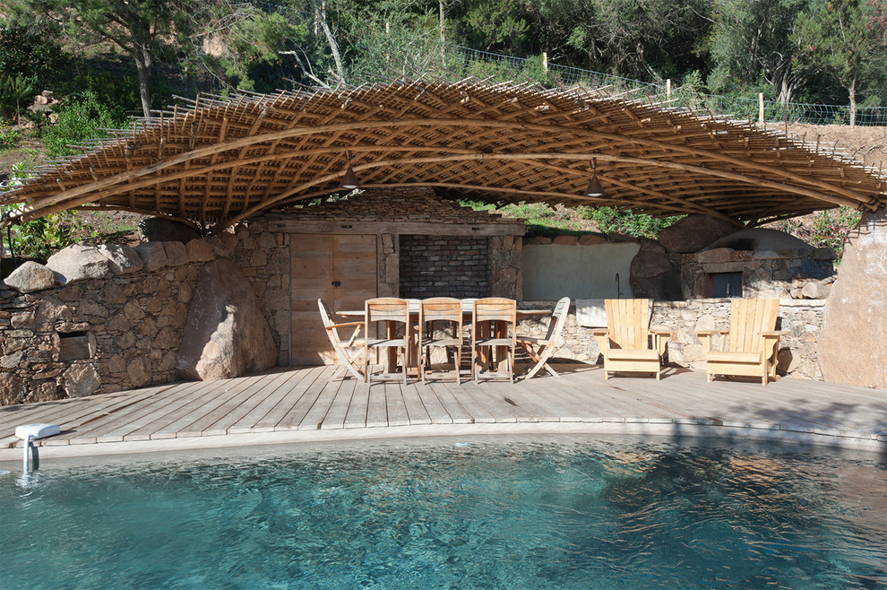 Ejemplo de casa de la piscina y piscina campestre rectangular en patio trasero con entablado