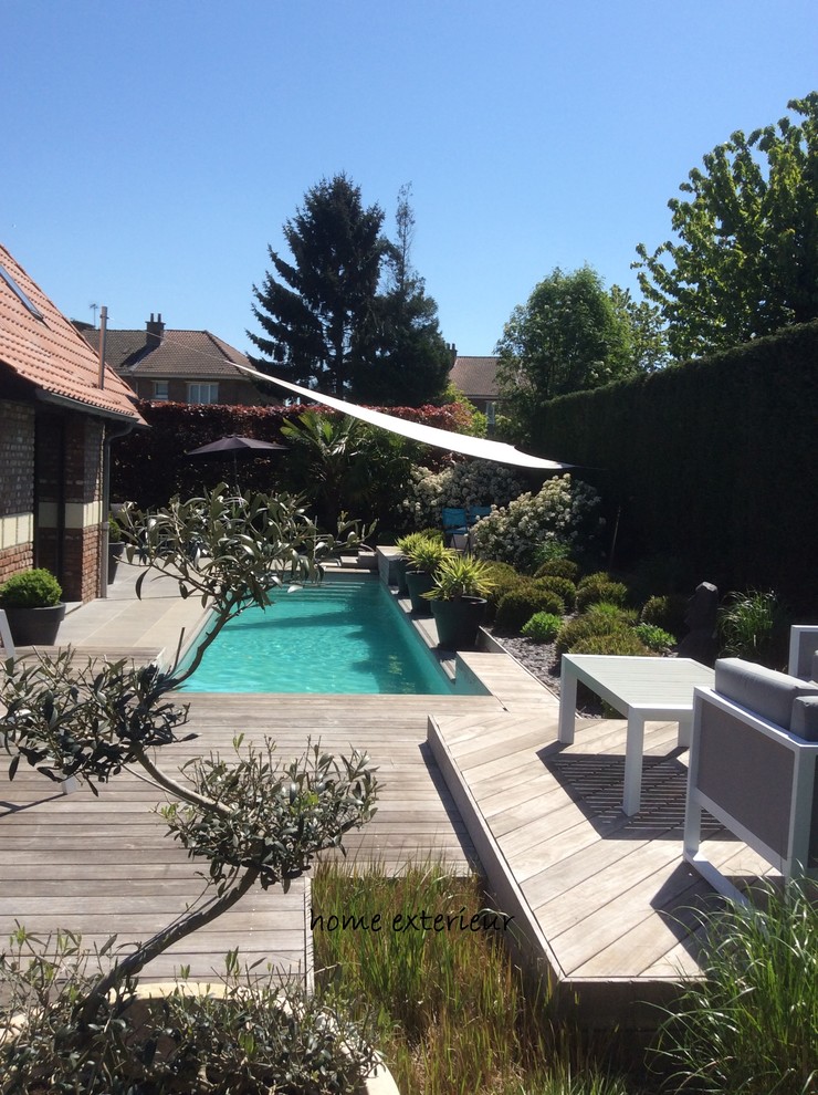 Ejemplo de piscina con tobogán alargada minimalista pequeña rectangular en patio trasero con entablado