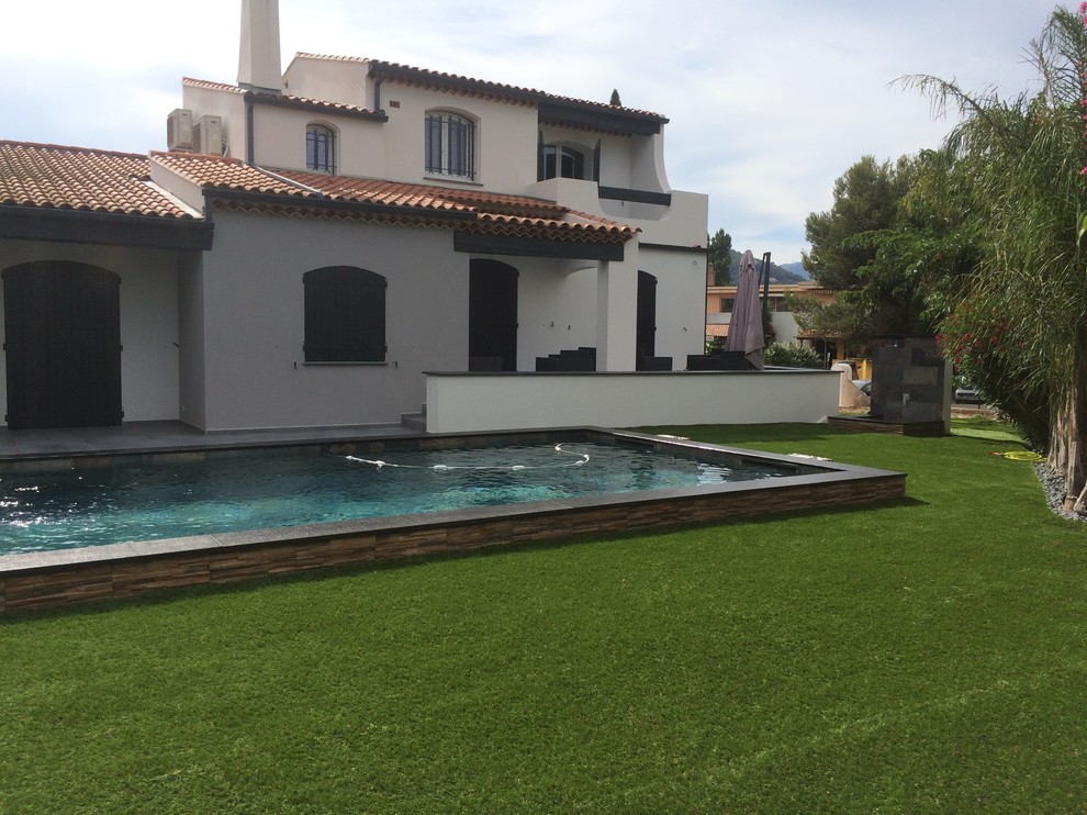 Ispirazione per una grande piscina naturale minimalista rettangolare davanti casa con piastrelle e fontane
