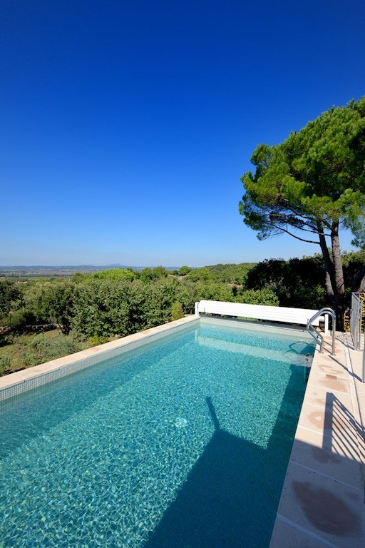 Réalisation d'une piscine à débordement méditerranéenne de taille moyenne et rectangle avec des pavés en pierre naturelle.
