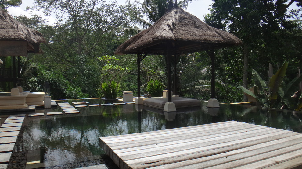 Imagen de piscina tropical grande a medida en patio trasero con entablado