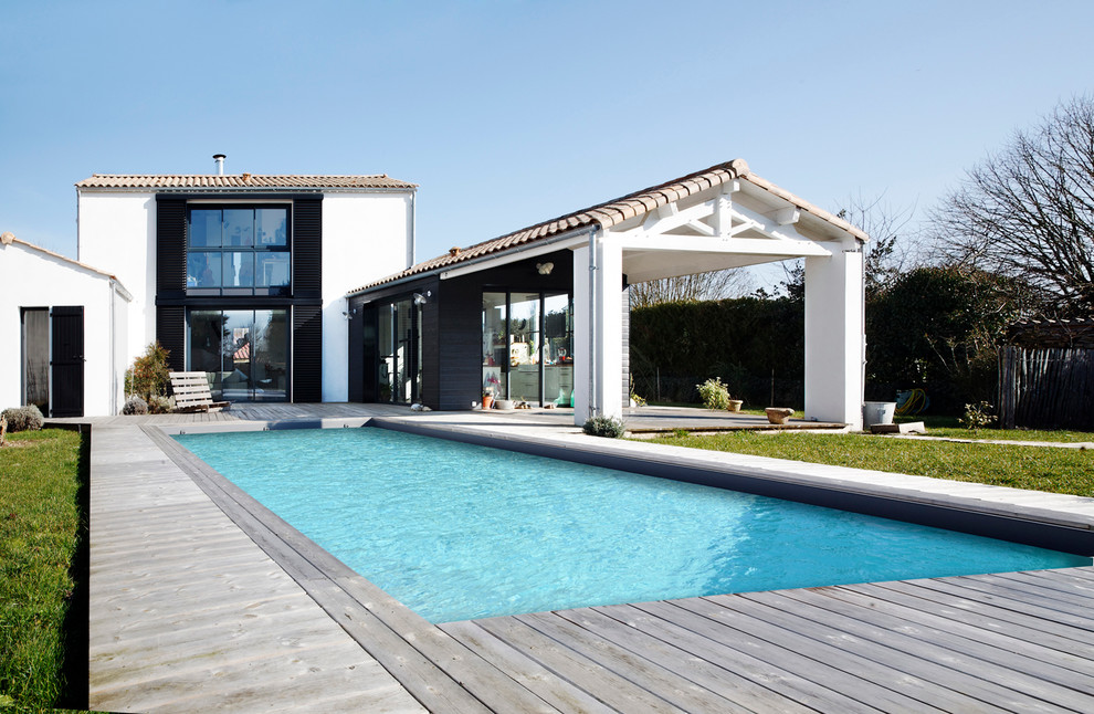 Inspiration pour une grande piscine arrière rustique rectangle avec une terrasse en bois.