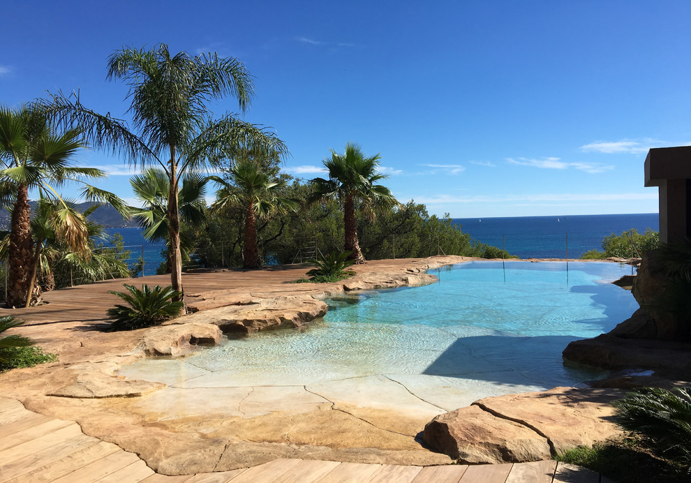 Inspiration pour une très grande piscine naturelle méditerranéenne sur mesure avec une terrasse en bois.