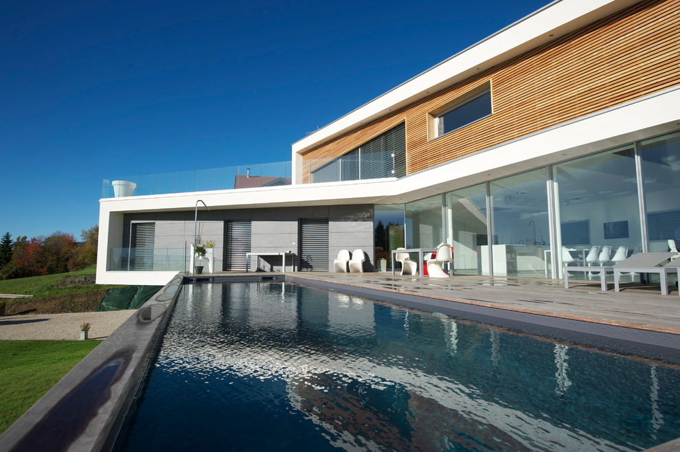 Expansive contemporary back rectangular lengths swimming pool in Lyon with decking.