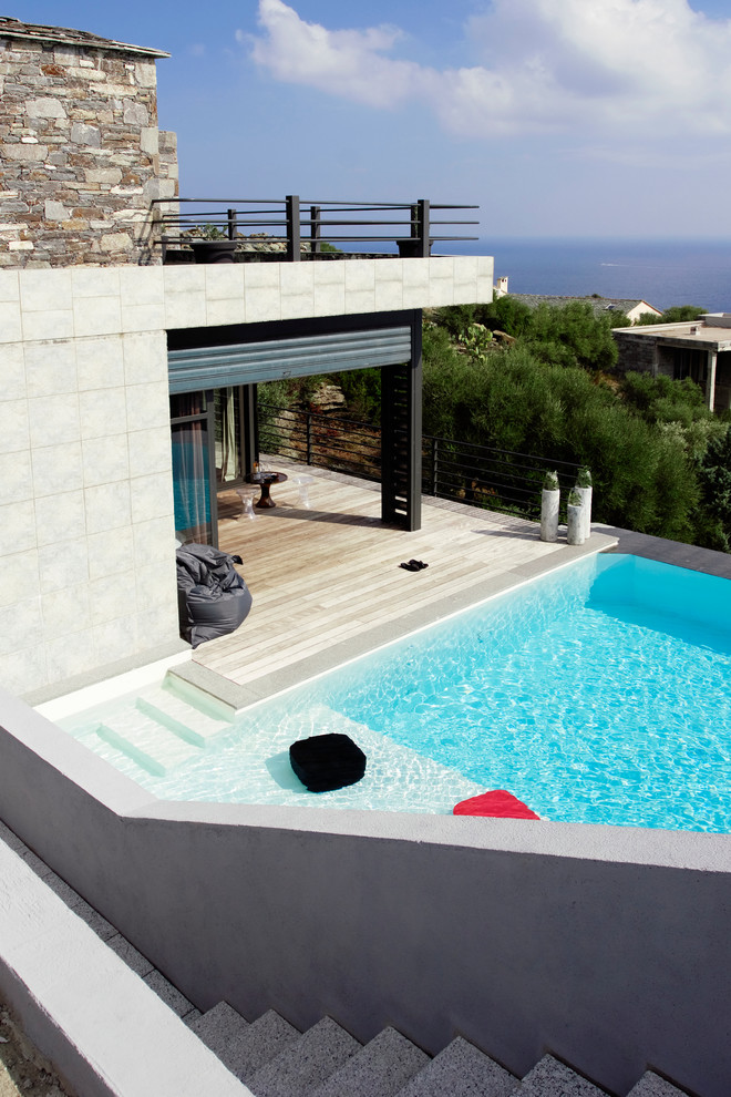 Diseño de piscina mediterránea de tamaño medio rectangular en patio trasero con entablado
