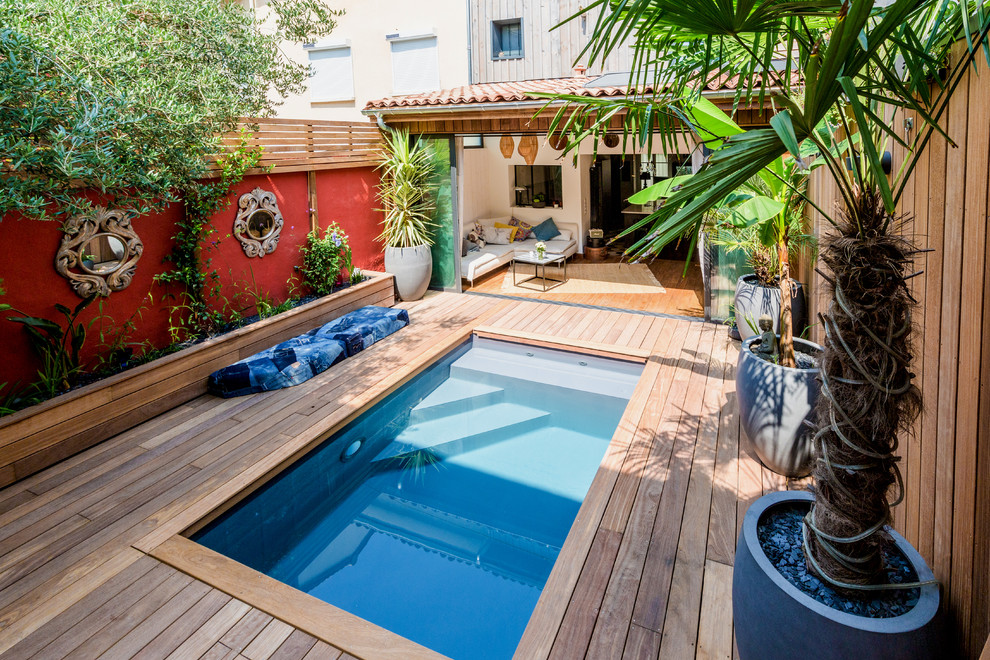 Ejemplo de piscina exótica pequeña en patio con entablado