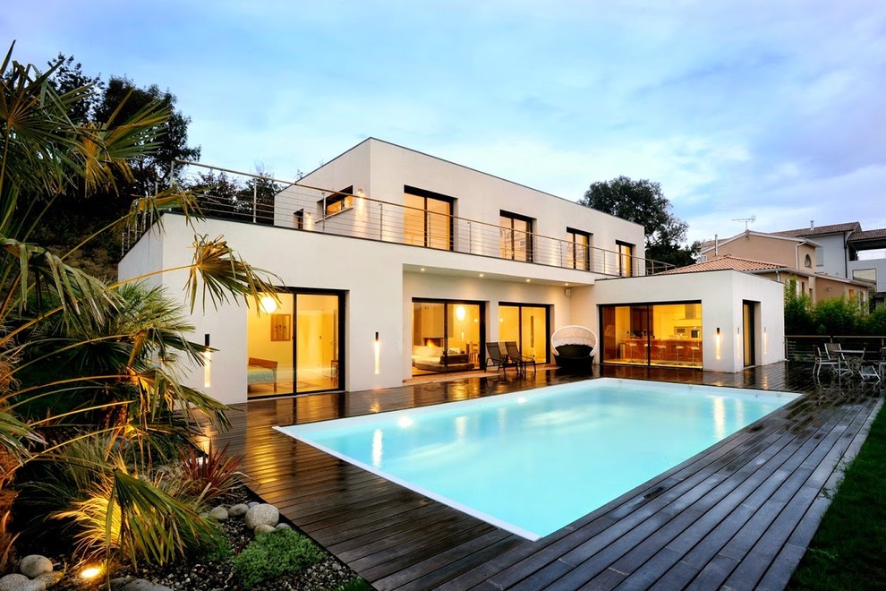 Modelo de casa de la piscina y piscina moderna de tamaño medio rectangular en patio trasero con entablado